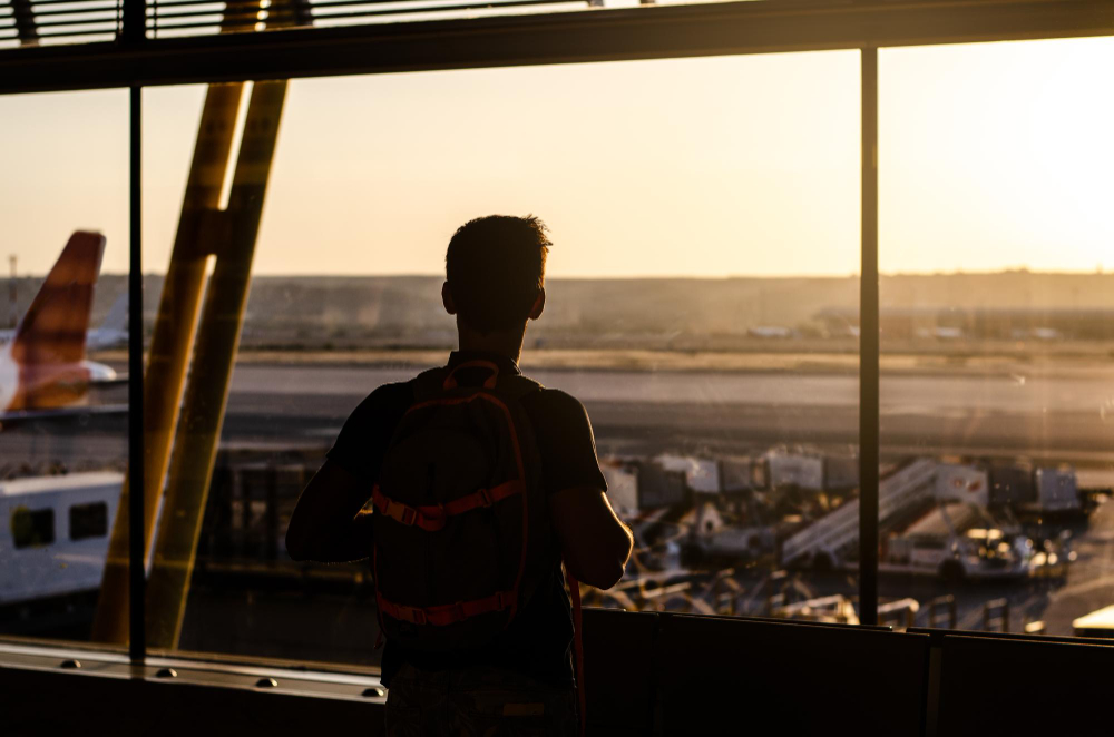 thoughtful-young-man-looking-by-window-airport-terminal