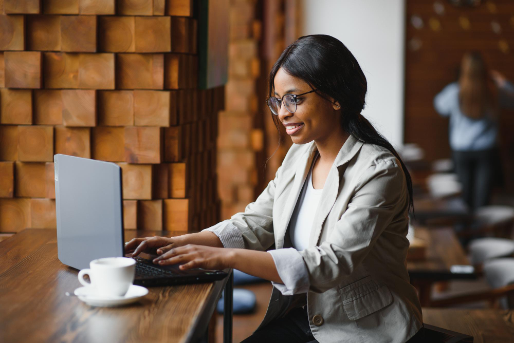 Black woman looking at laptop in a cafe