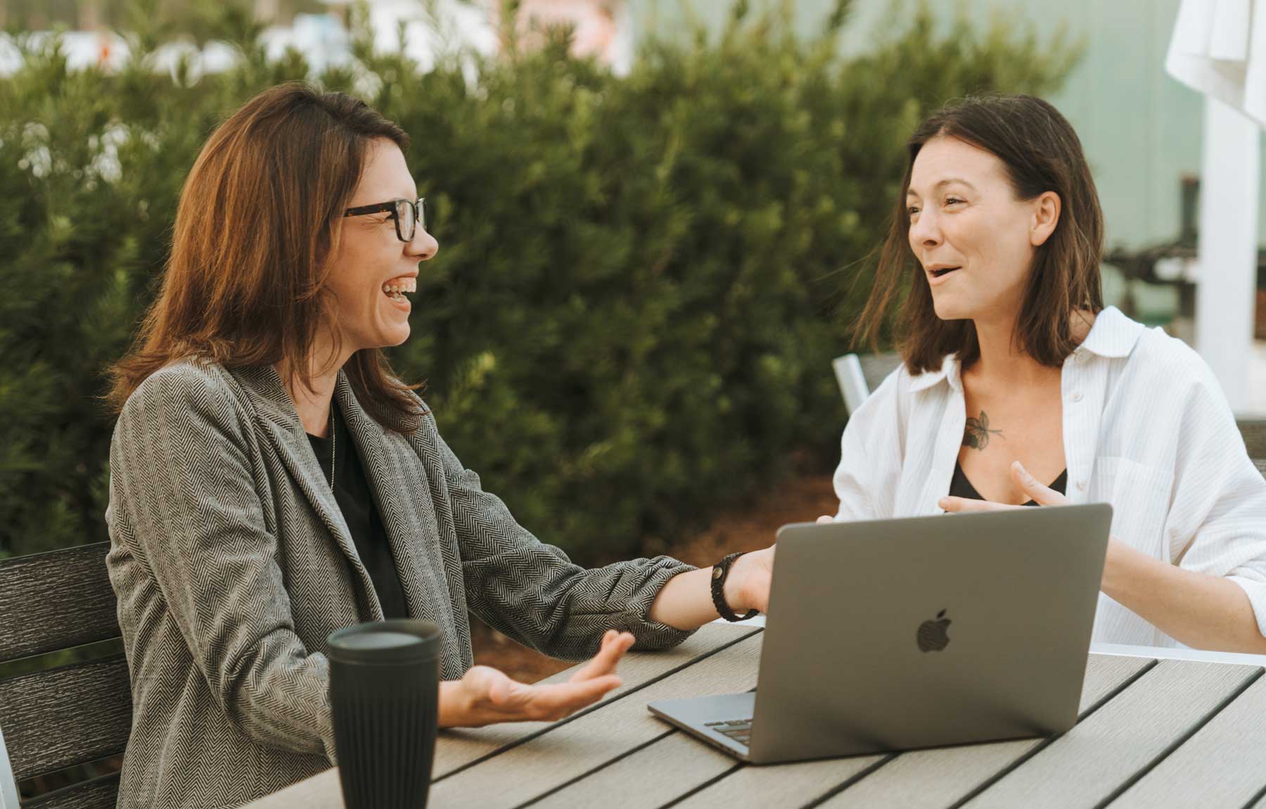 Business woman and man working on a laptop project holding coffee mugs